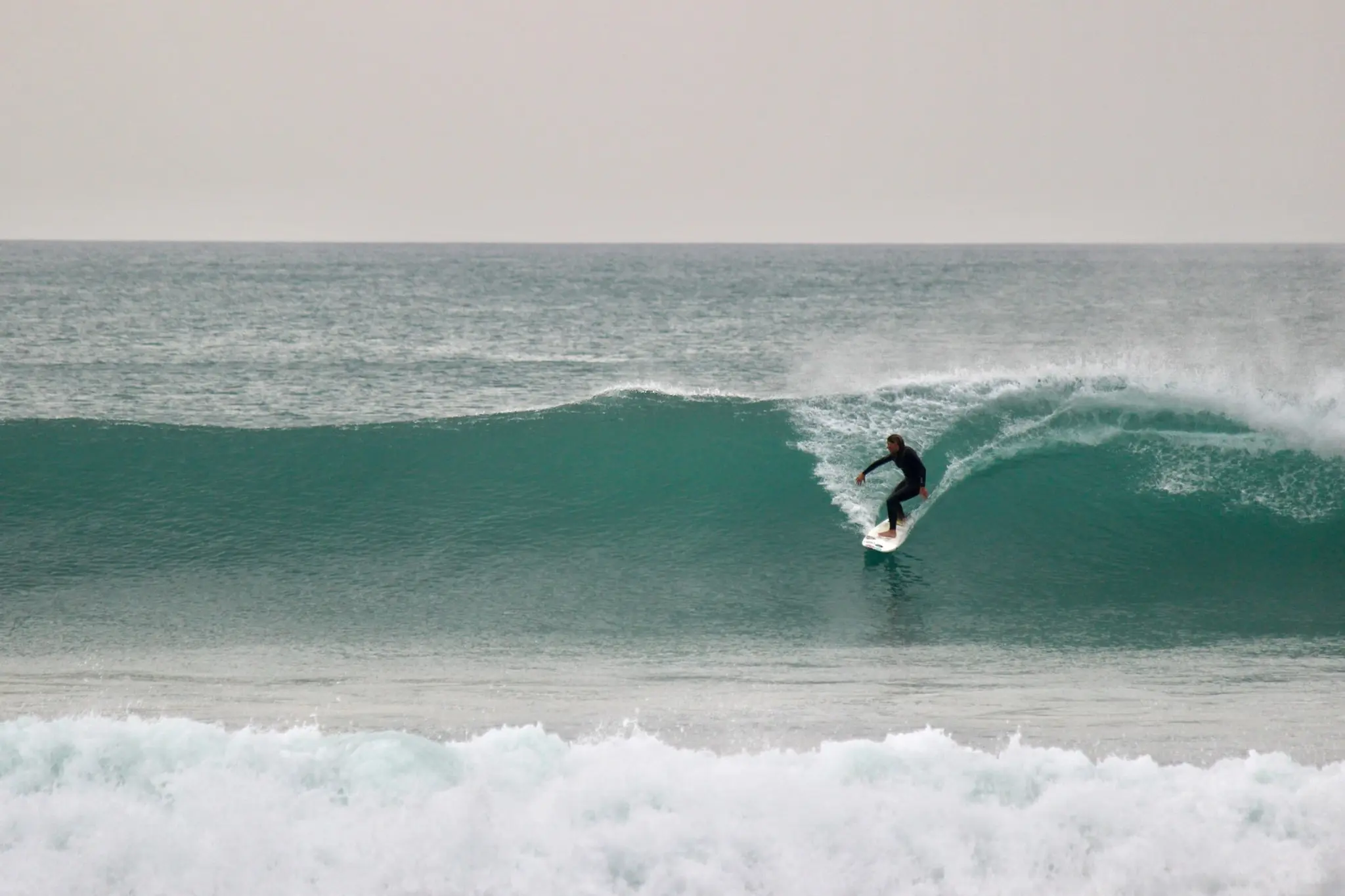 Inês surfing across a green wave