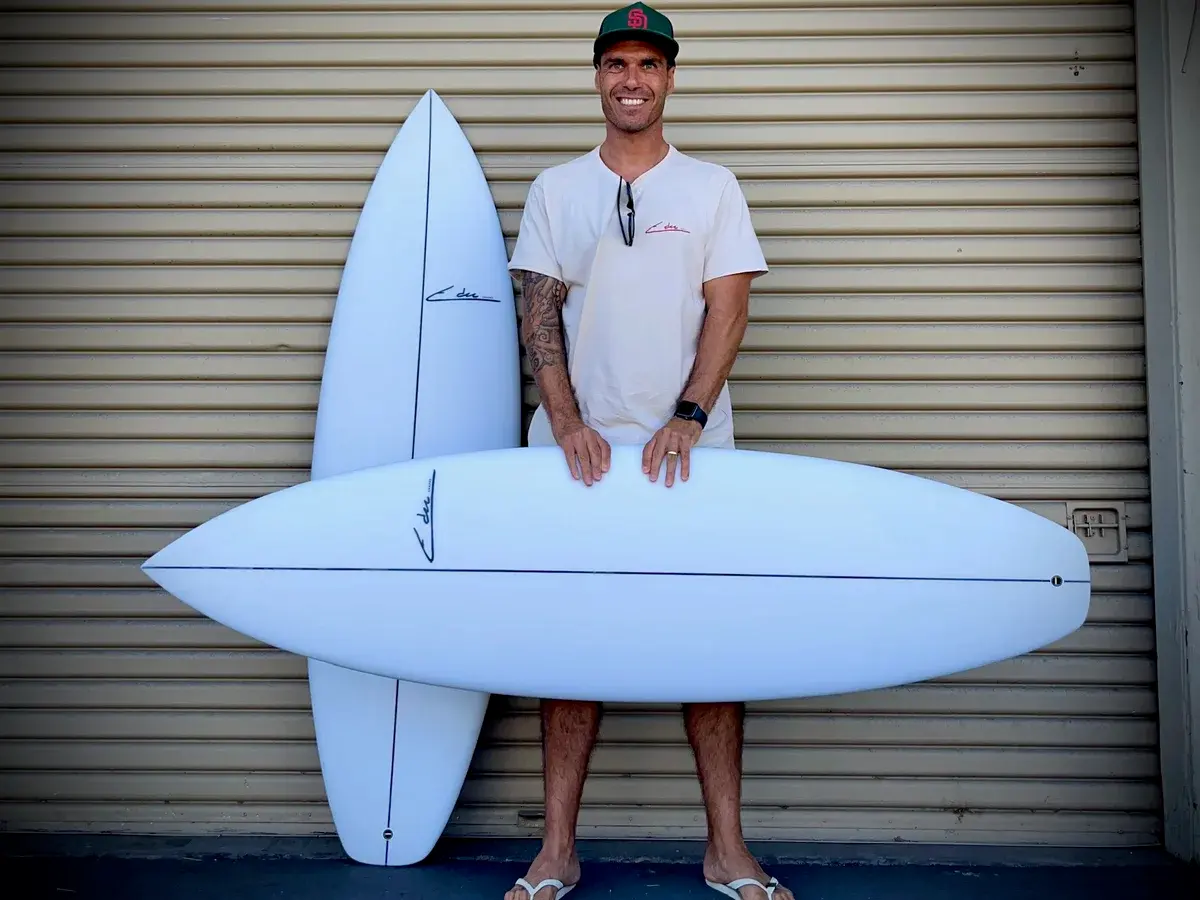 Edu standing with two of his surfboards