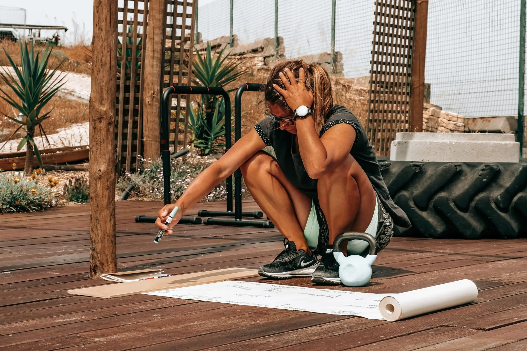 Inês reviewing training notes beside exercise equipment outdoors